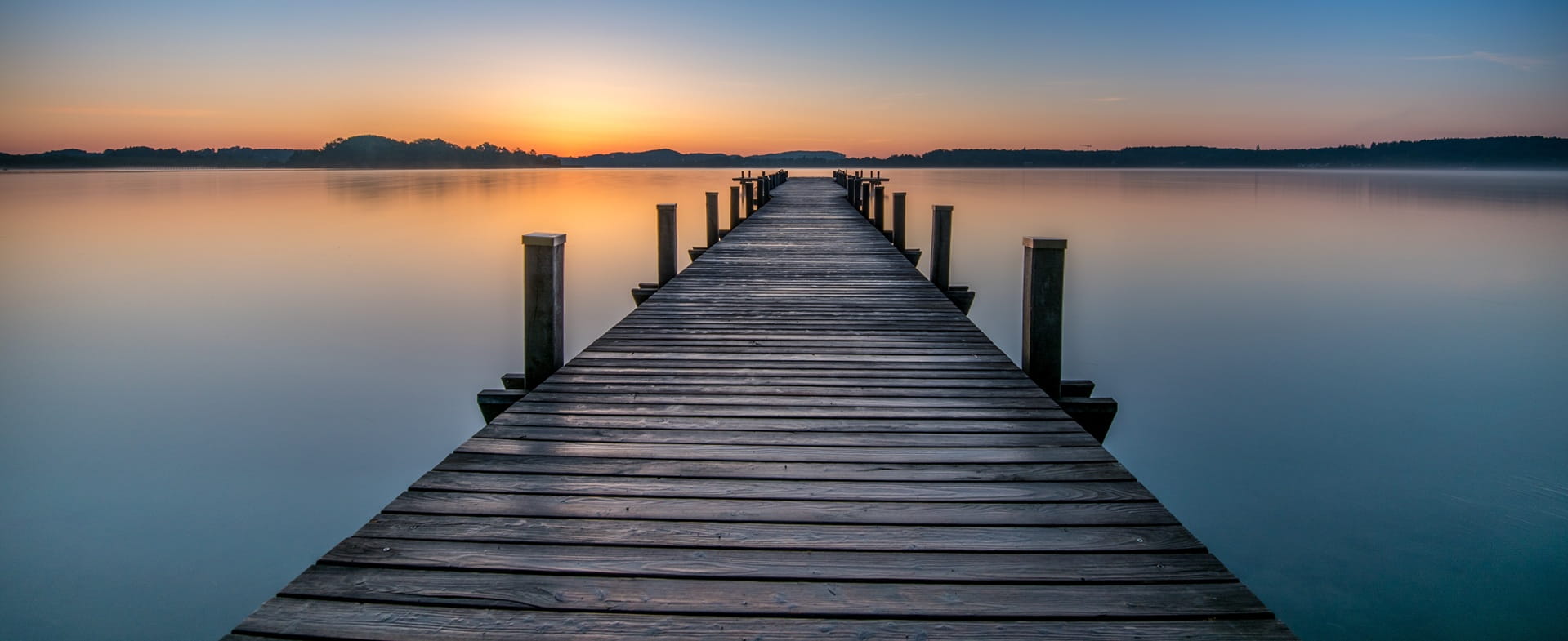 ponton en bois sur un lac au soleil couchant